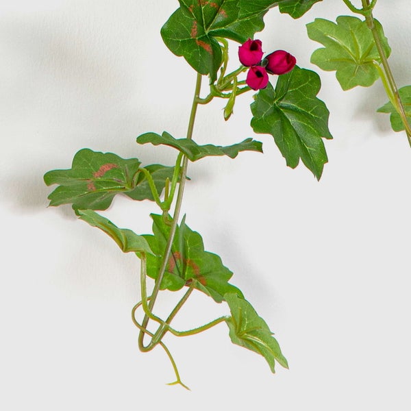 Künstliche Hängepflanze mit grünen Blättern und pinkfarbenen Blütenknospen.