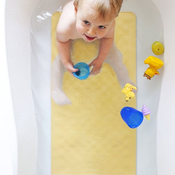 Kind mit Badespielzeug und Badewanneneinlage in der Badewanne