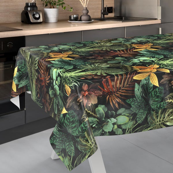 Tischdecke mit tropischem Blättermuster und Blüten auf einem Küchentisch in einer modernen Küche mit grauen Fronten.