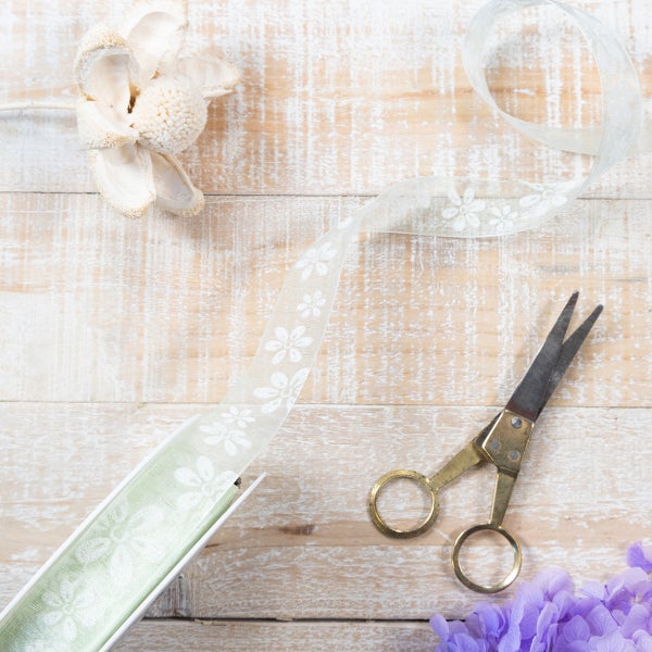 Weißes Geschenkband mit Blumenmuster, Breite 25 Millimeter.