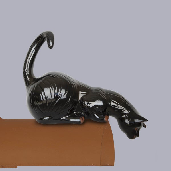 Firstfigur Katze aus glasierter Keramik, liegend auf einem braunen Firstziegel.