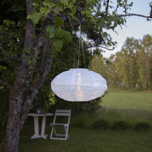 Wohnraum mit drei schwarzen Hängelampen, einem Stuhl, Beistelltischen und einer Zimmerpflanze