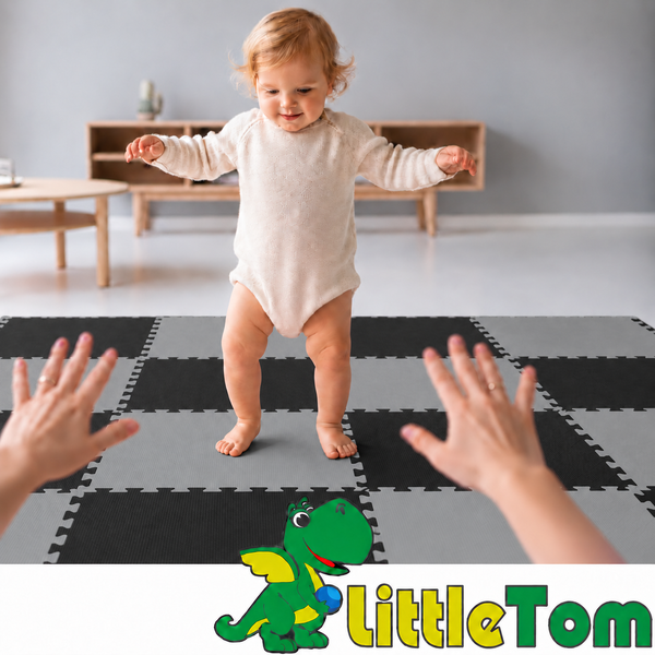 Ein Kleinkind steht auf einer schachbrettartigen Schaumstoffmatte als Bodenbelag, während es von Erwachsenenhänden unterstützt wird. LittleTom Logo.