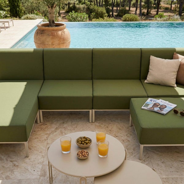 Modulares Garten-Lounge-Sofa mit olivgrünen Polstern und weißem Gestell auf einer sonnigen Terrasse am Pool, inklusive rundem Beistelltisch.
