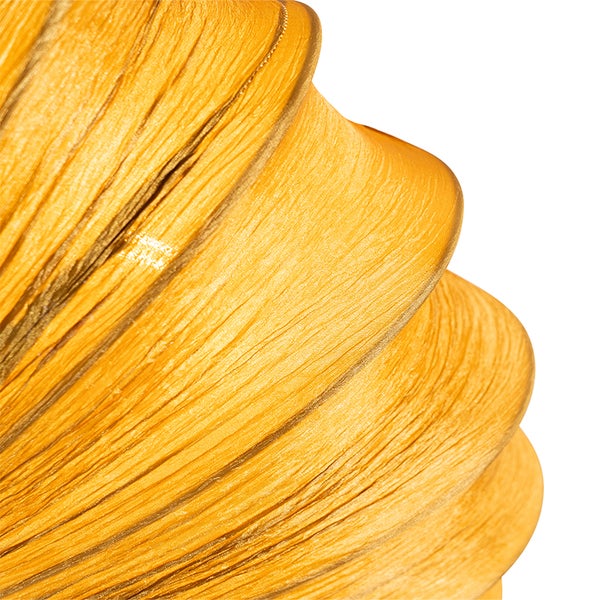 Detailansicht eines strukturierten, gewellten Lampenschirms aus goldfarbenem Material.