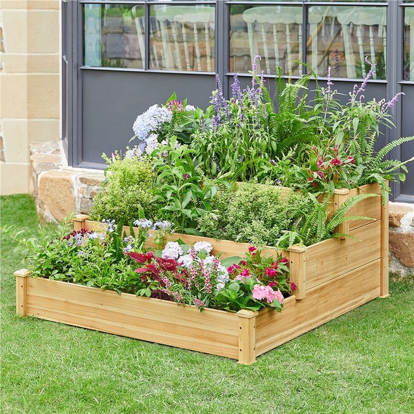 Holzpflanzkasten mit drei Ebenen und bepflanzt mit verschiedenen Blumen und Pflanzen auf Rasenfläche.