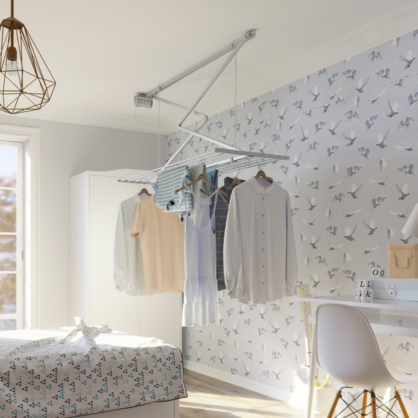 Deckenwäscheständer mit Wäsche in einem hellen Schlafzimmer.