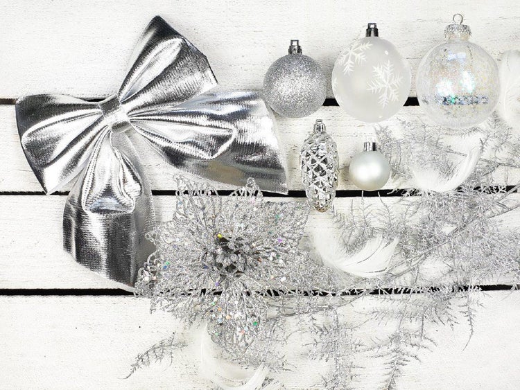 Weihnachtsdekoration Set mit silberner Schleife, Glitzerkugeln, Tannenzapfen, Weihnachtsstern und künstlichen Zweigen auf Holzuntergrund.