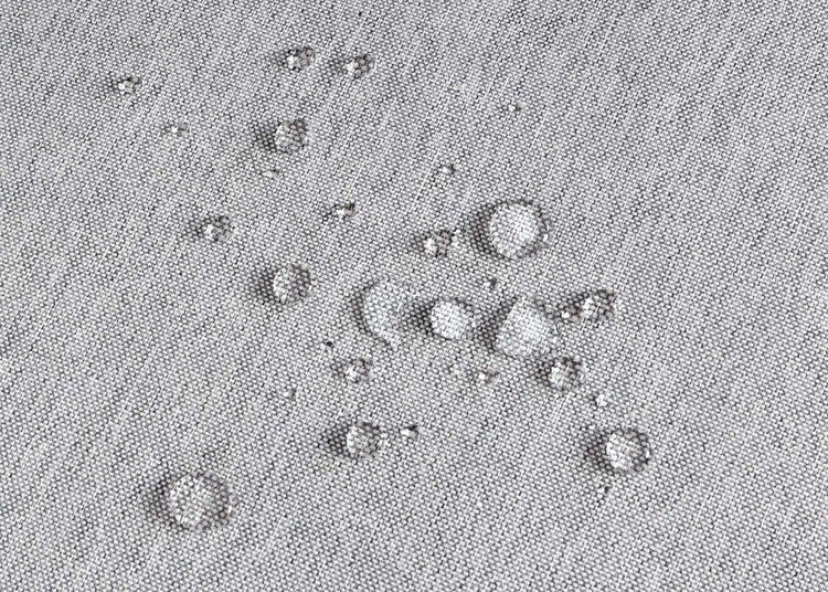 Wassertropfen auf einem wasserabweisenden, gewebten Stoff.