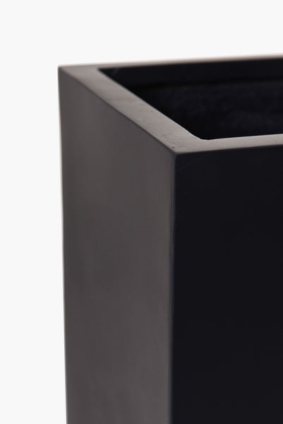 Detailaufnahme der Ecke eines schwarzen, eckigen Pflanzkübels mit glatter Oberfläche.