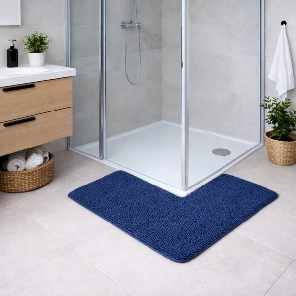 Dunkelblaue Badematte in L-Form vor einer Glasduschkabine in einem hellen, modern eingerichteten Badezimmer mit Holzmöbeln.