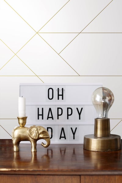 Dekorative Szene mit einer Leuchtbox, einer Elefantenkerze und einer dekorativen Glühbirne auf einem Holztisch