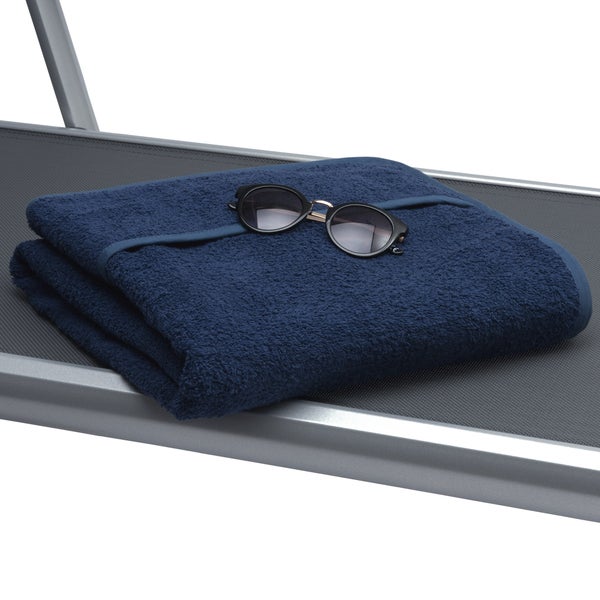 Gestapeltes blaues Handtuch mit Sonnenbrille auf einer Sonnenliege