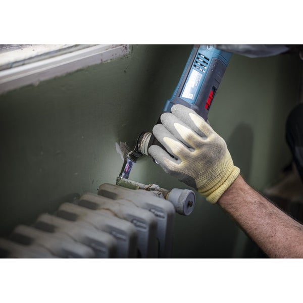 Handwerker demontiert Heizungsrohr mit einer oszillierenden Säge