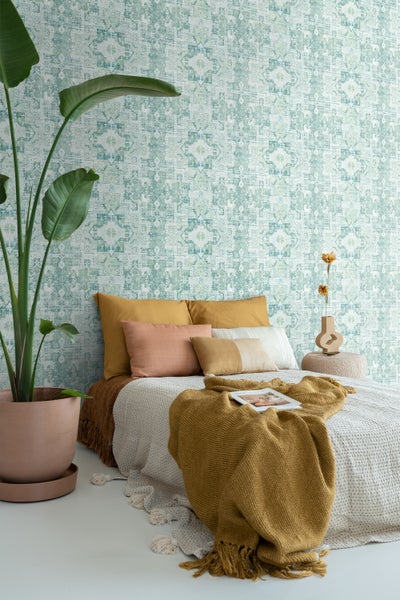 Schlafzimmer mit orientalisch gemusterter Tapete, Bett und Zimmerpflanze