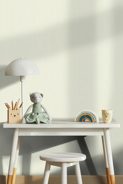 Gestreifte Tapete in einem hellen Kinderzimmer mit Schreibtisch, Hocker, Lampe, Stofftier und Holzspielzeug.