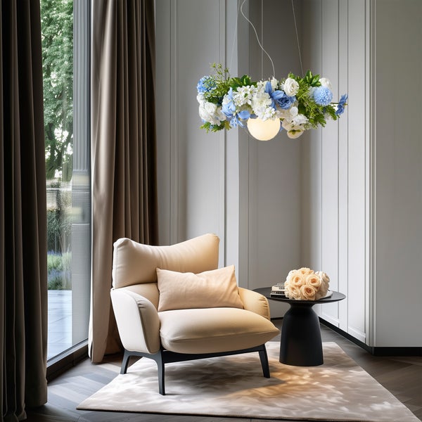 Hell eingerichtetes Zimmer mit beigem Sessel, schwarzem Beistelltisch und Pendelleuchte mit floralem Dekor und leuchtender Kugel.