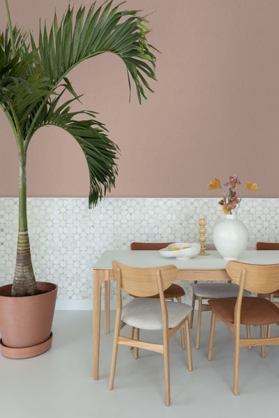 Szene mit Esstisch, Stühlen, Palme im Topf und dekorativen Elementen für ein stilvolles Interieur