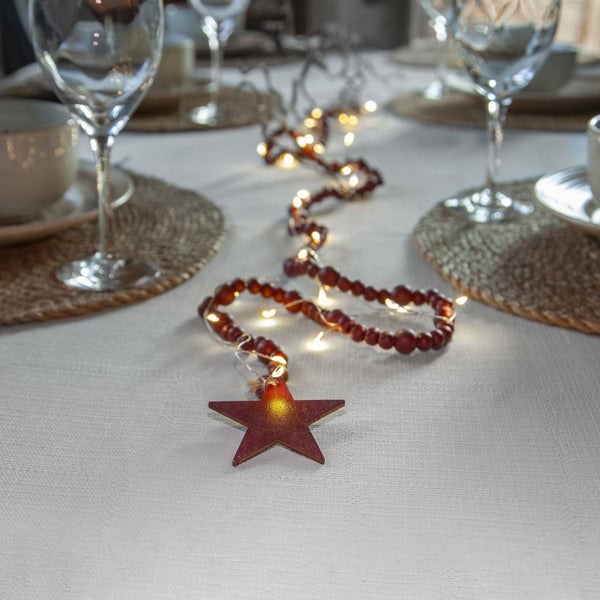 Dekorierter Tisch mit Glaswaren, Geschirr, Platzdeckchen und Lichterkette mit Sternanhänger