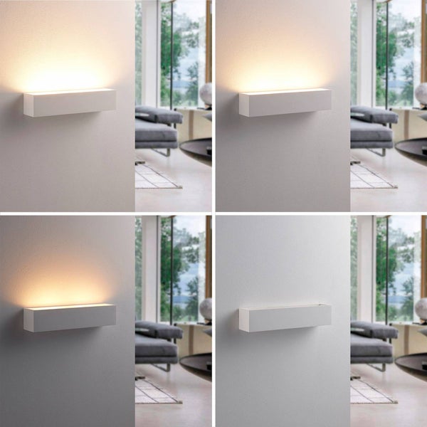 Rechteckige LED-Wandleuchte in vier Lichtstärken an einer Wand in einem hellen, modernen Wohnzimmer mit Sofa und Fenster im Hintergrund.
