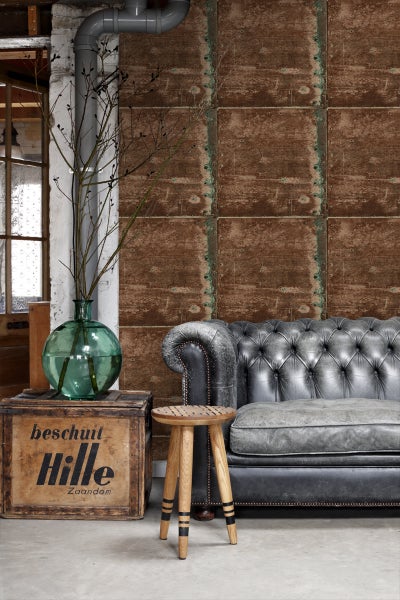 Wohnzimmer mit brauner Wandverkleidung, Ledersofa und Holzhocker