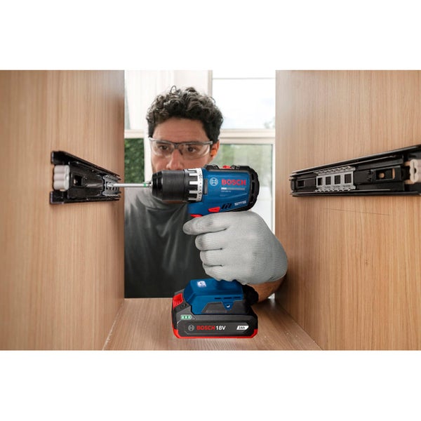 Handwerker mit Schutzbrille verwendet einen Bosch Akku Bohrschrauber zur Montage von Schubladenschienen in einem Holzschrank.