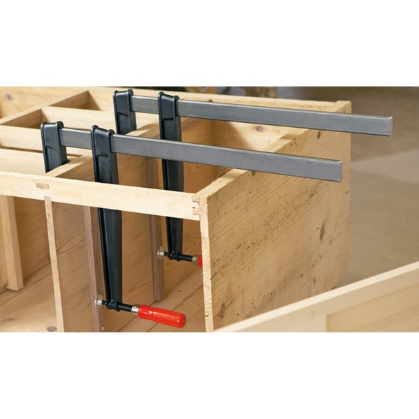 Zwei Stangenzwingen fixieren ein Holzbauteil.