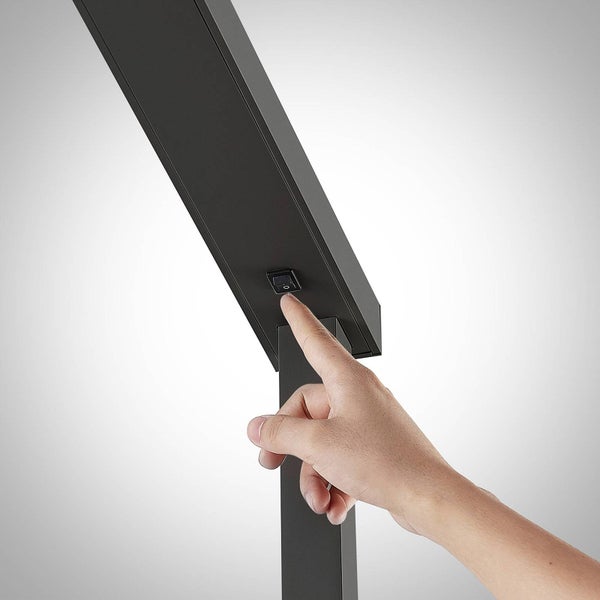 Nahaufnahme einer Hand, die den Wippschalter an einer schwarzen Stehlampe betätigt.