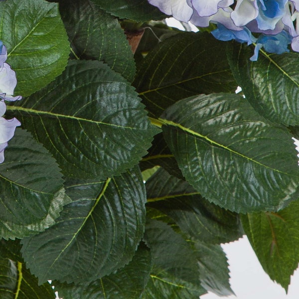 Nahaufnahme einer künstlichen Hortensie mit grünen Blättern und blauen Blüten.