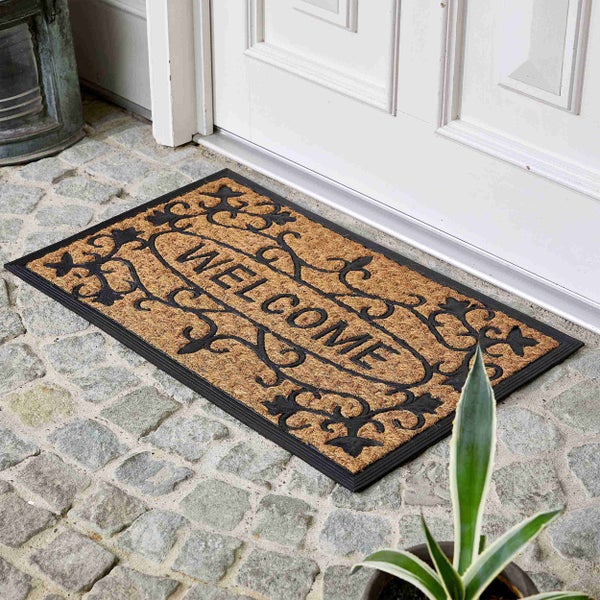 Fußmatte mit Willkommensaufschrift vor einer Haustür