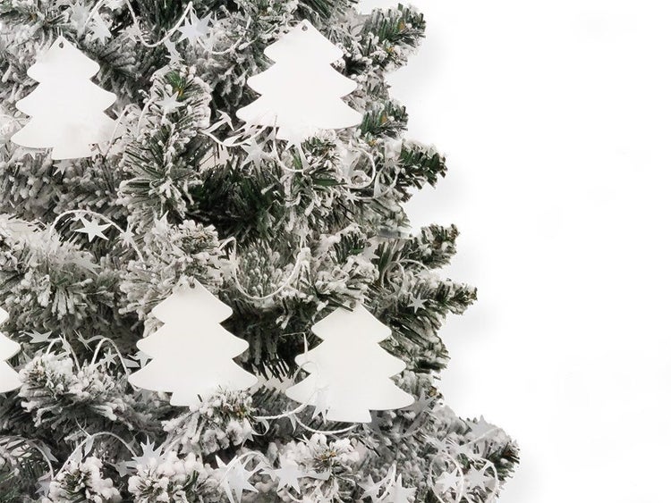 Weihnachtsbaumschmuck in Form von Tannenbäumen an einem künstlichen, beschneiten Tannenbaum mit Sternengirlande.