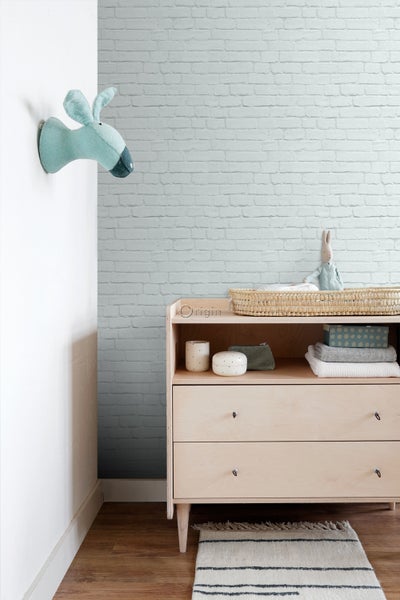Kinderzimmer mit Wickelkommode, Spielzeug und Ziegelsteintapete