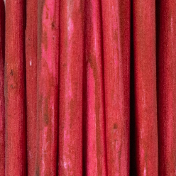 Nahaufnahme von vertikal angeordneten, rot gefärbten Bambusstäben mit natürlicher Holzstruktur.