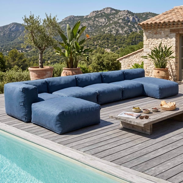 Modulares Outdoor-Lounge-Sofa aus blauem Stoff auf einer Holzterrasse neben einem Pool mit Blick auf die Berge.