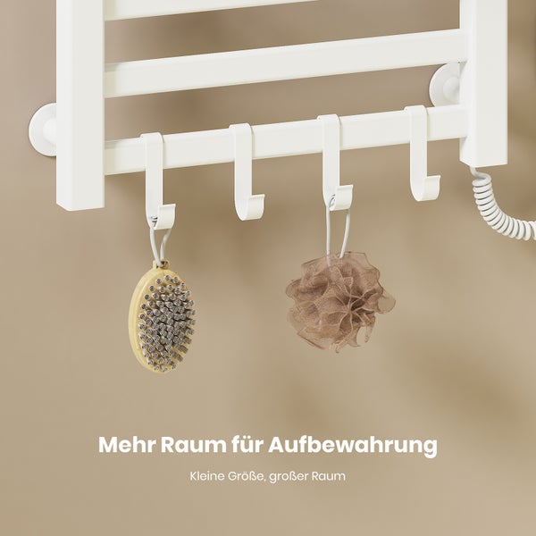 Weiße Haken an einem Handtuchheizkörper im Badezimmer, behängt mit einer Körperbürste und einem Duschschwamm.