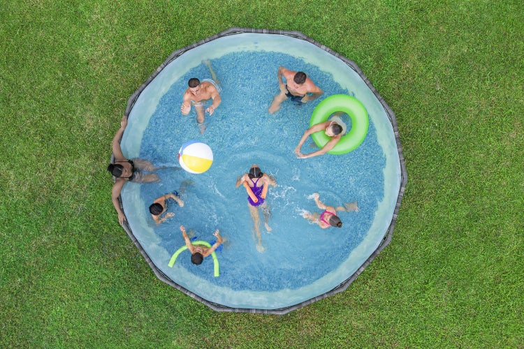 Rundes Rahmenpool Set auf einer grünen Rasenfläche mit spielenden Personen und Wasserzubehör aus der Vogelperspektive.