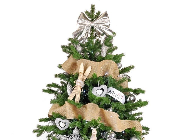 Geschmückter künstlicher Weihnachtsbaum mit einer großen Schleife als Spitze, Juteband und winterlichen Dekorationselementen.