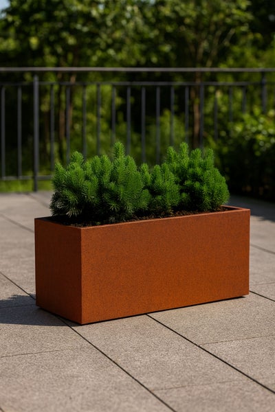 Rechteckiger Pflanzkasten in Rostoptik aus Stahl mit Pflanzen auf einer Terrasse mit Steinfliesen und einem Metallgeländer.