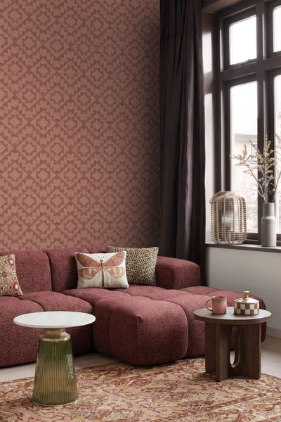 Wohnzimmer mit gemusterter Vliestapete, einem texturierten Sofa und zwei kleinen Beistelltischen vor einem Fenster mit dunklen Vorhängen.