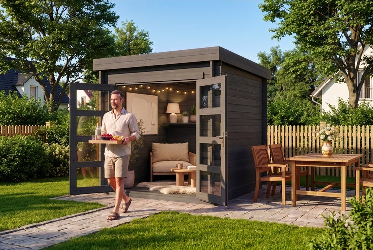 Modernes dunkelgraues Gartenhaus aus Holz mit Flachdach und Glastüren, eingerichtet als gemütlicher Rückzugsort in einem sonnigen Garten.