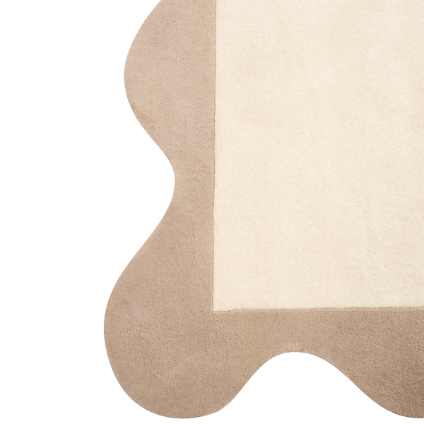 Weicher Teppich mit gewelltem Rand in Beige und Creme aus plüschigem Material.
