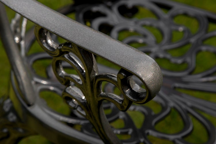 Detailaufnahme einer Gartenbank aus Metall mit dekorativen Verzierungen.