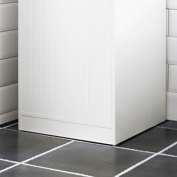 Weißer Badezimmerschrank auf gefliestem Boden vor gefliester Wand