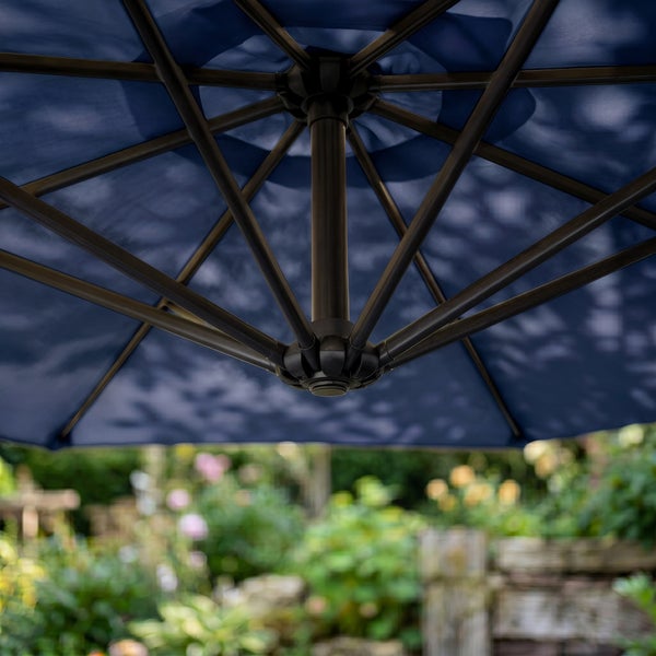 Detailansicht der Rahmenkonstruktion eines Sonnenschirms mit Metallstreben und Mittelmast vor einem Garten.