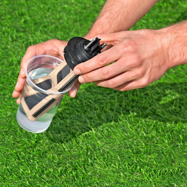 Person reinigt einen Teichfilter in einem mit Wasser gefüllten Behälter.