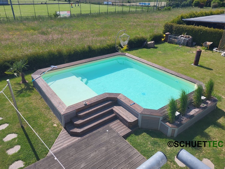 Rechteckiger Gartenpool mit Holzumrandung, integrierter Treppe und angrenzendem Holzdeck in einer gepflegten Gartenanlage.