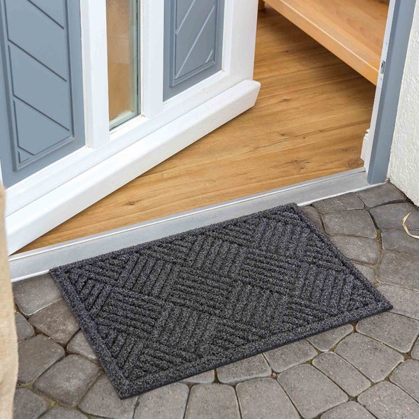 Fußmatte vor einer Haustür auf Pflastersteinen