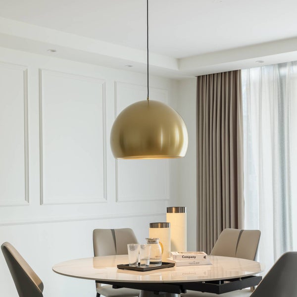 Goldfarbene Pendelleuchte in einem hellen, modernen Esszimmer über einem Marmortisch mit grauen Stühlen.