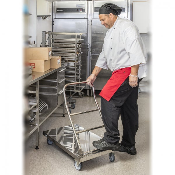 Ein Koch schiebt einen Servierwagen aus Edelstahl in einer Großküche.
