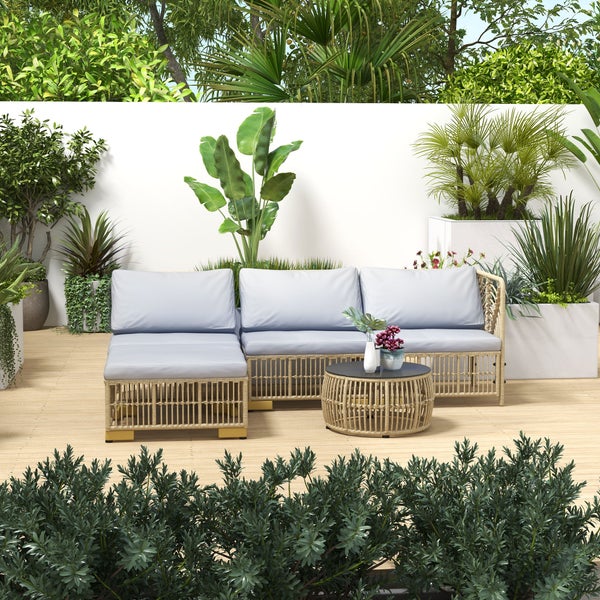 Gartenlounge-Set mit Rattansofa, Tisch und Pflanzen auf einer Terrasse